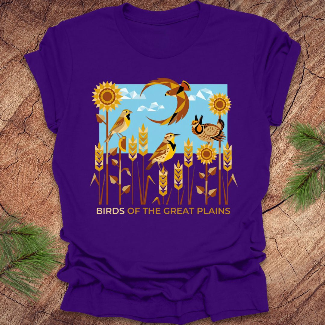 Purple t-shirt with 'Birds of the Great Plains' design featuring birds, sunflowers, and a moon on a wooden surface.