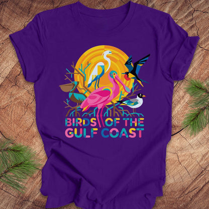 Purple t-shirt with bird design and text, 'birds of the gulf coast' on a wooden background.