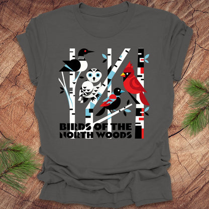 Gray t-shirt with bird design and 'Birds of the North Woods' text on a wooden surface.