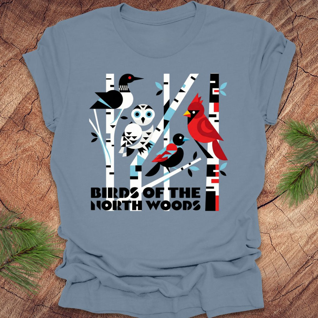 Blue t-shirt with bird design and 'Birds of the North Woods' text on a wooden background