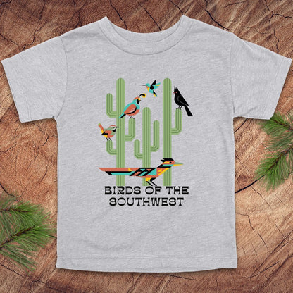 Gray toddler t-shirt with 'Birds of the Southwest' design featuring cacti and birds on a wooden surface.