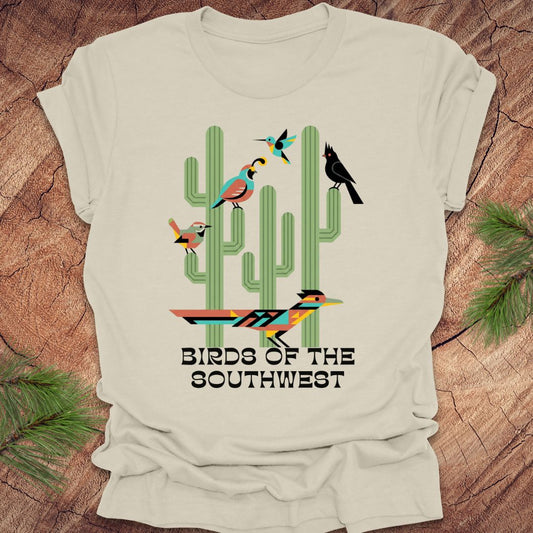 Beige t-shirt with 'Birds of the Southwest' design featuring cacti and birds on a wooden surface.