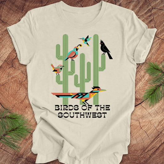 Beige t-shirt with 'Birds of the Southwest' design featuring cacti and birds on a wooden surface.