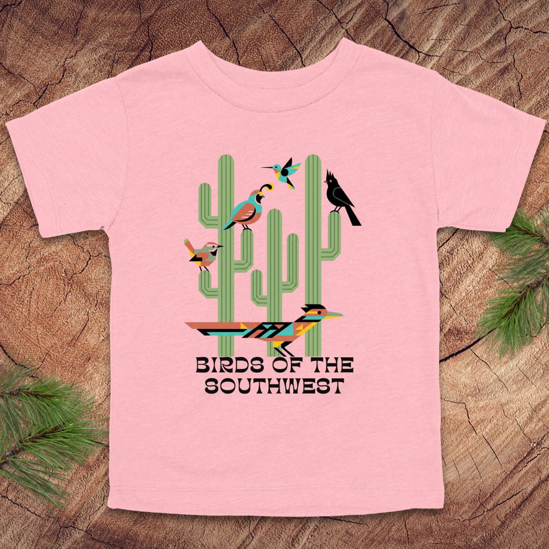Pink toddler t-shirt with 'Birds of the Southwest' design featuring cacti and birds on a wooden surface.