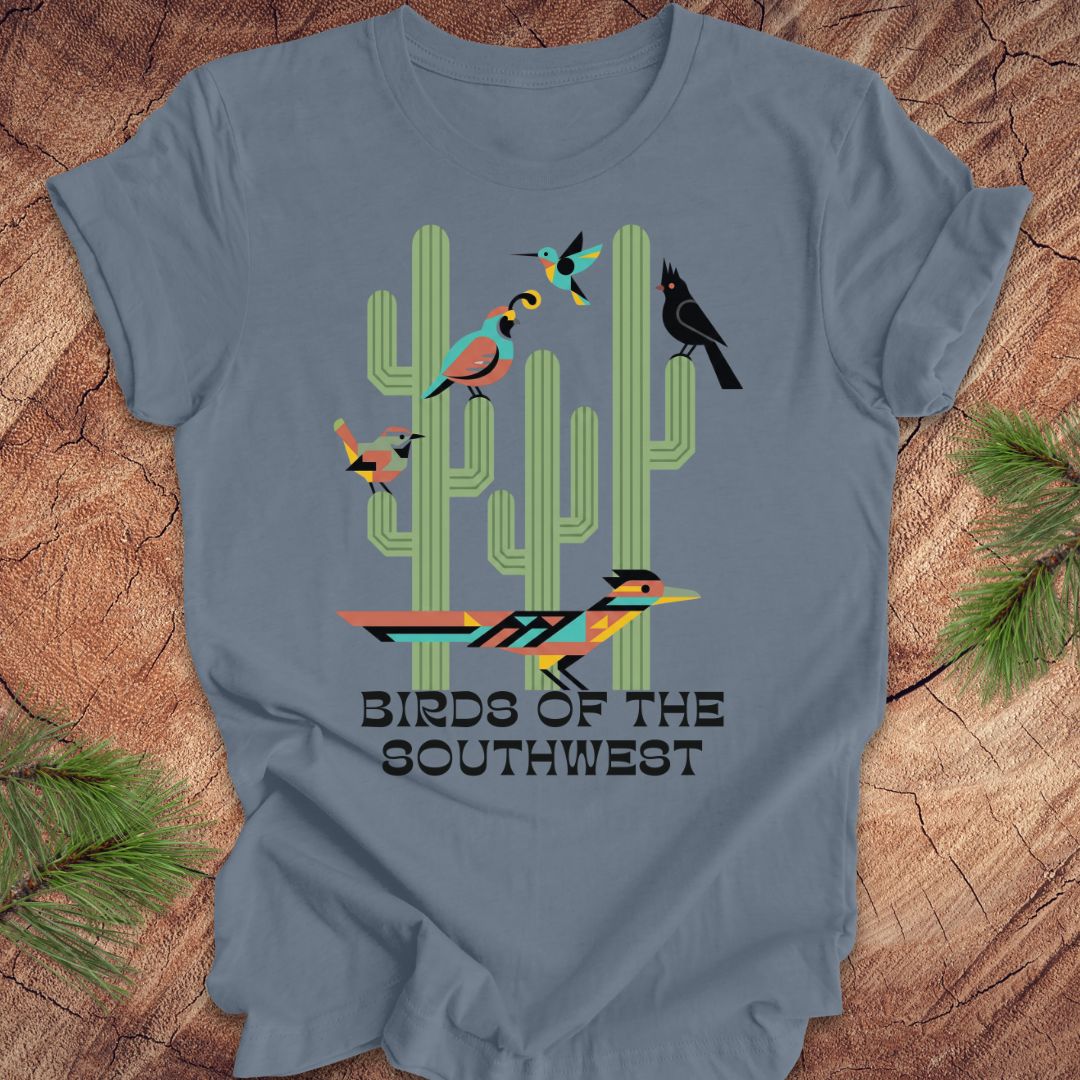 Blue t-shirt with a graphic of cacti and birds on a wooden surface