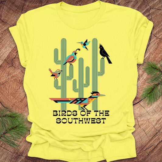 Yellow t-shirt with cactus and bird design on a wooden surface