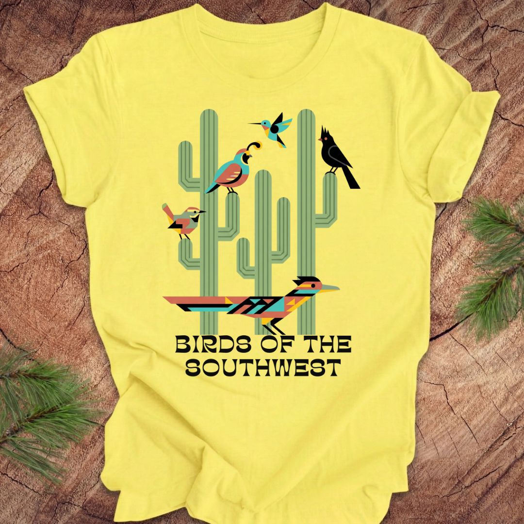 Yellow t-shirt with 'Birds of the Southwest' design featuring cacti and birds on a wooden surface.