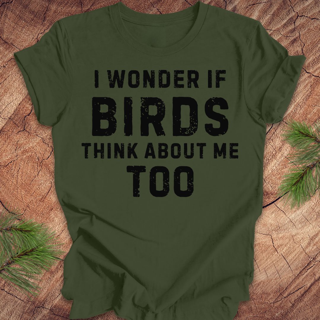 Green t-shirt with text 'I wonder if birds think about me too' on a wooden surface.