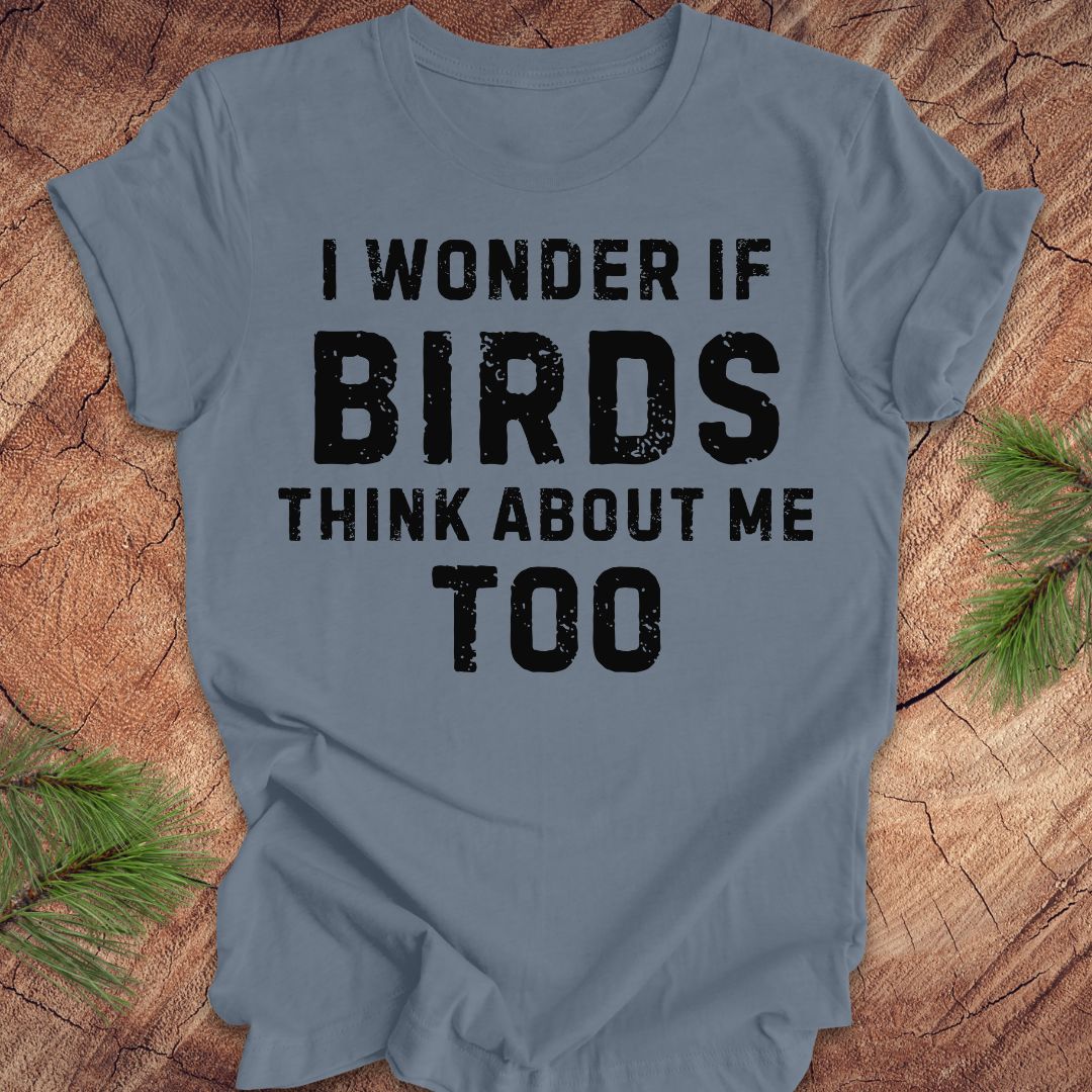 Blue t-shirt with text 'I wonder if birds think about me too' on a wooden surface.