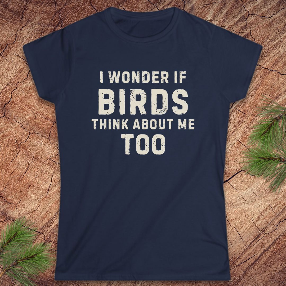 Navy blue t-shirt with white text 'I wonder if birds think about me too' on a wooden surface.