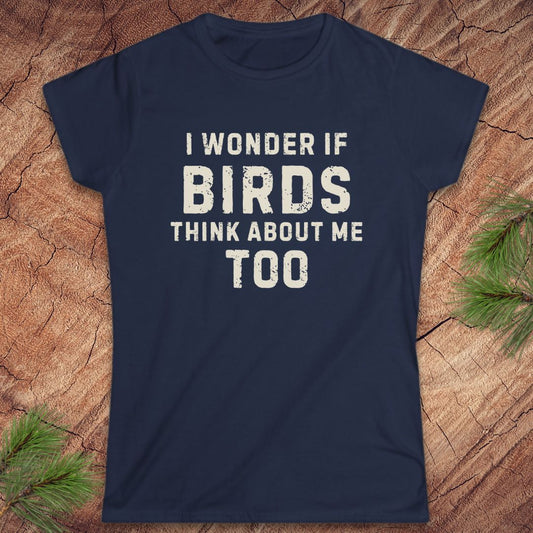 Navy blue t-shirt with white text 'I wonder if birds think about me too' on a wooden surface.