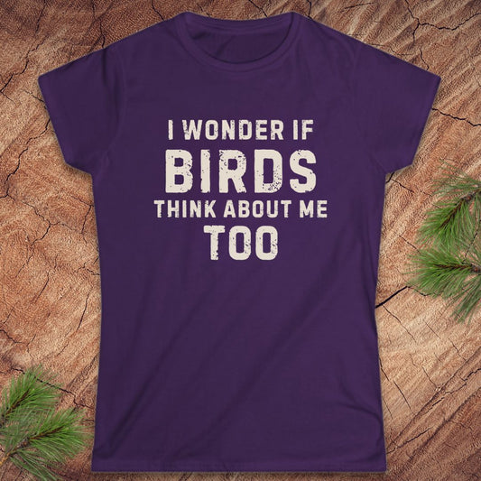 Purple t-shirt with white text 'I wonder if birds think about me too' on a wooden surface.
