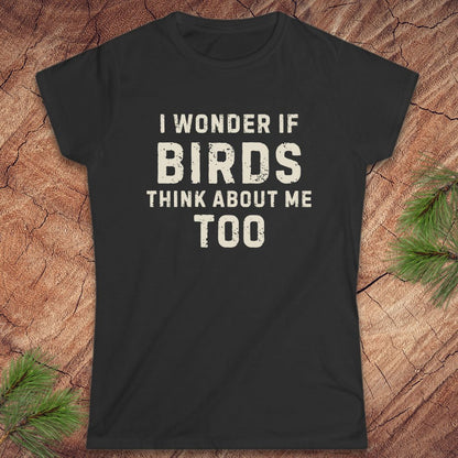 Black t-shirt with white text 'I wonder if birds think about me too' on a wooden surface.