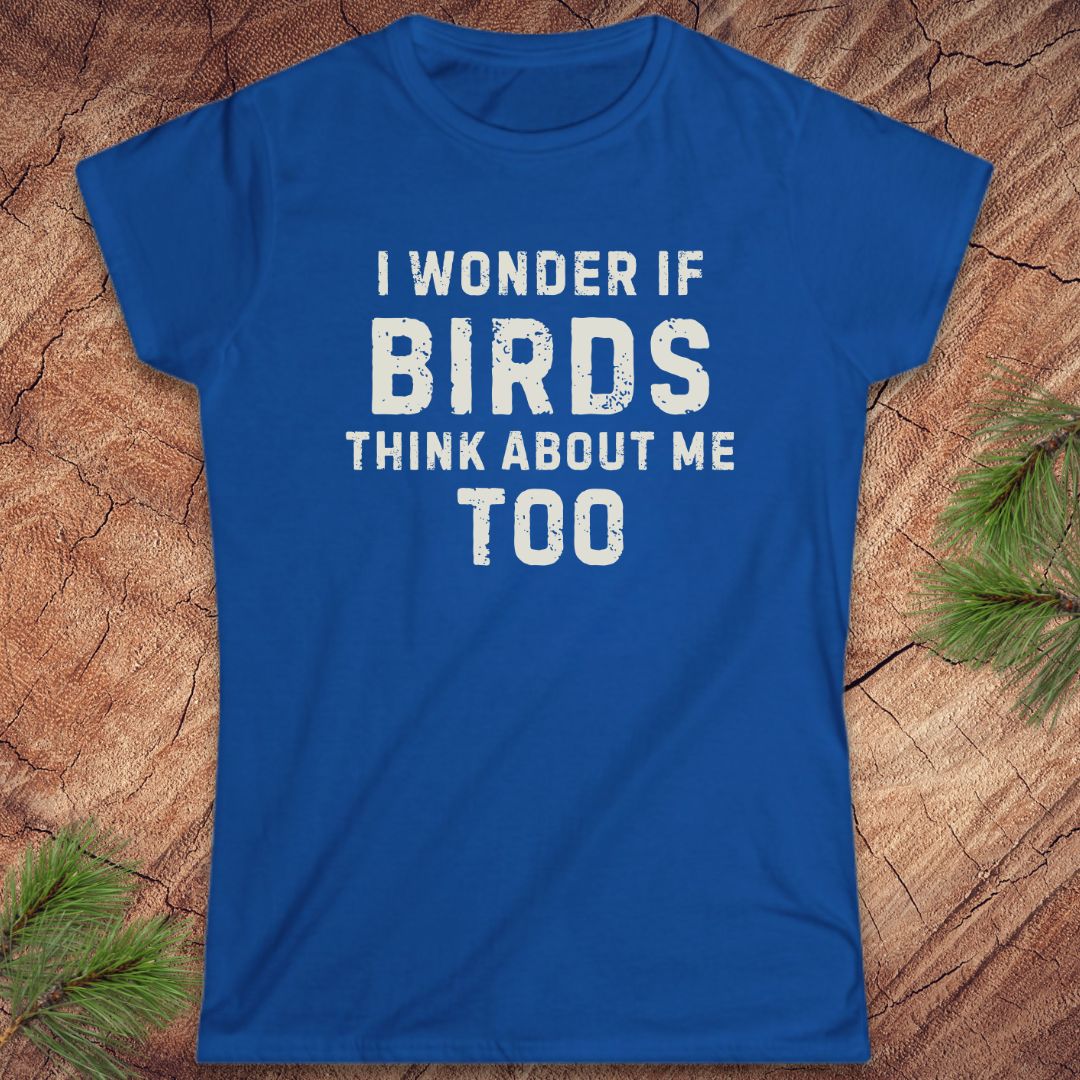 Blue t-shirt with white text 'I wonder if birds think about me too' on a wooden surface.