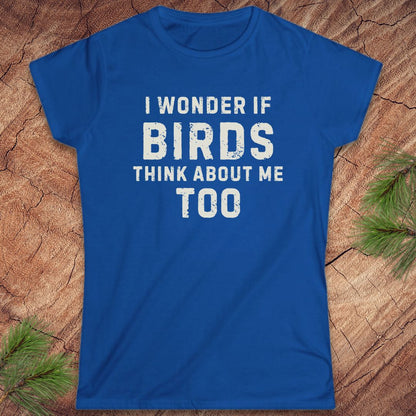 Blue t-shirt with white text 'I wonder if birds think about me too' on a wooden surface.