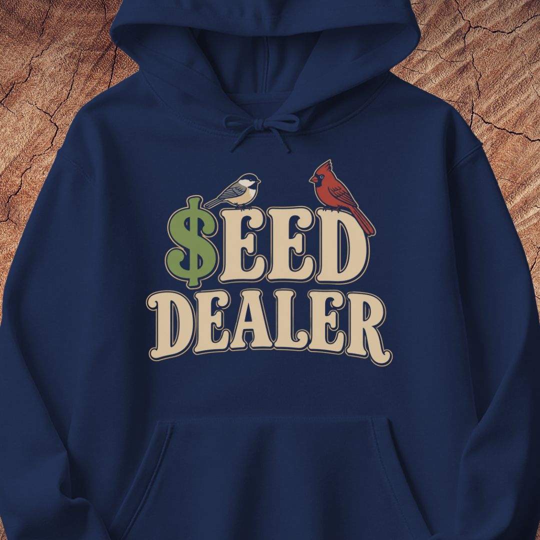 A navy blue pullover hoodie featuring a graphic print on the chest that reads 'SEED DEALER' with a green dollar sign and two birds (a chickadee and a cardinal) perched on the letters, shown against a textured wood background.