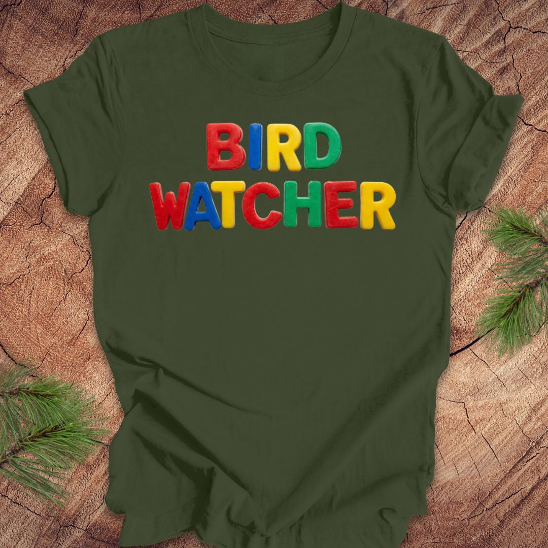 Green t-shirt with 'BIRD WATCHER' in colorful letters on a wooden background