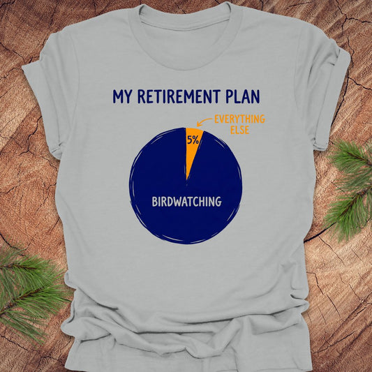 Gray t-shirt with a birdwatching retirement plan pie chart design on a wooden surface