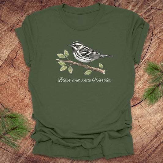 Green t-shirt with a black-and-white warbler design on a wooden surface