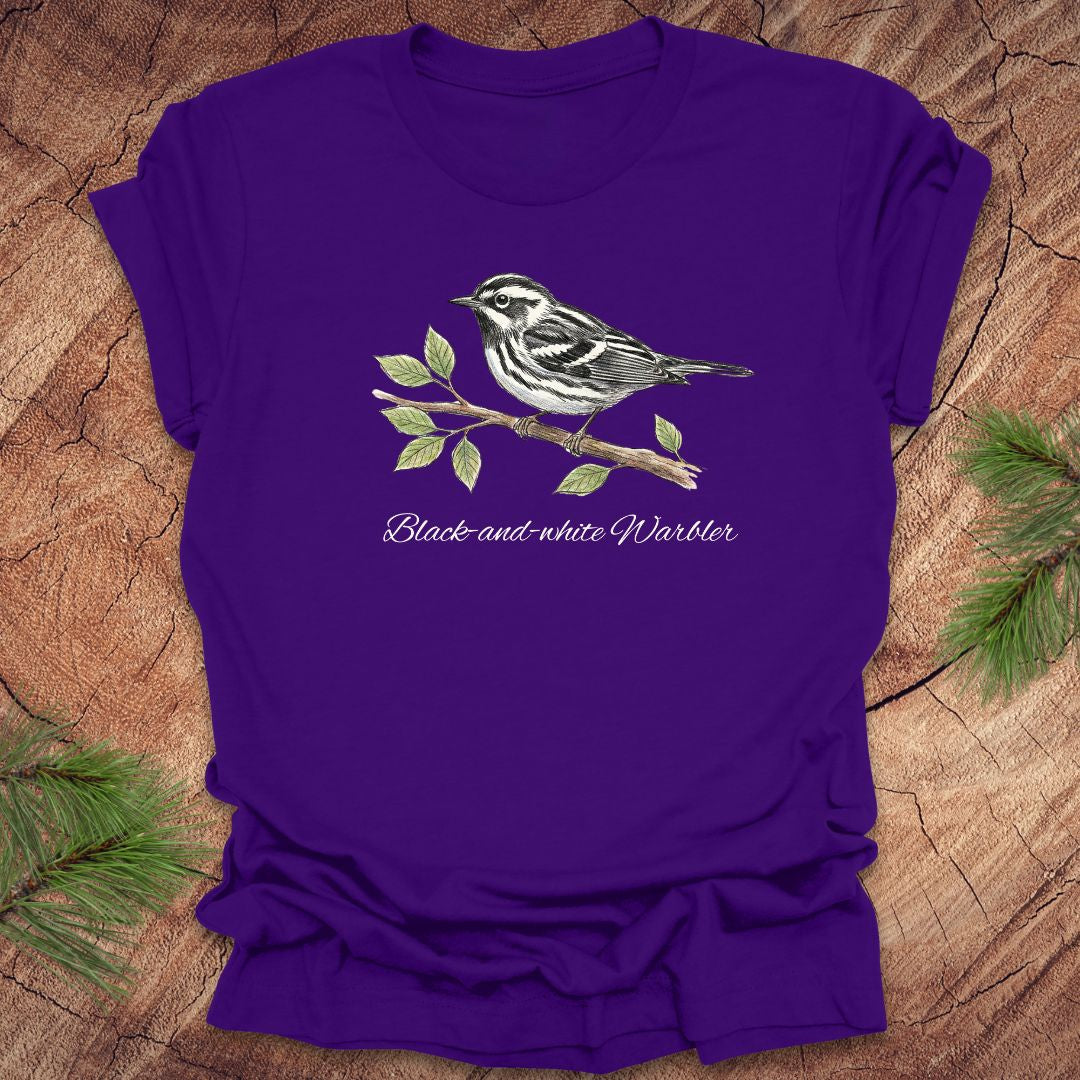 Purple t-shirt with a black and white warbler design on a wooden surface