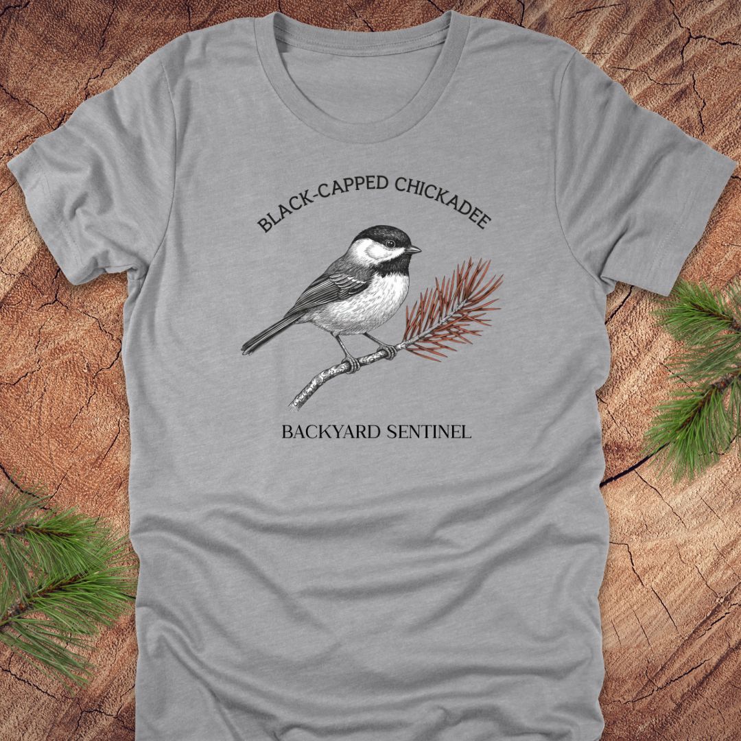 Gray t-shirt with black-capped chickadee design on a wooden surface