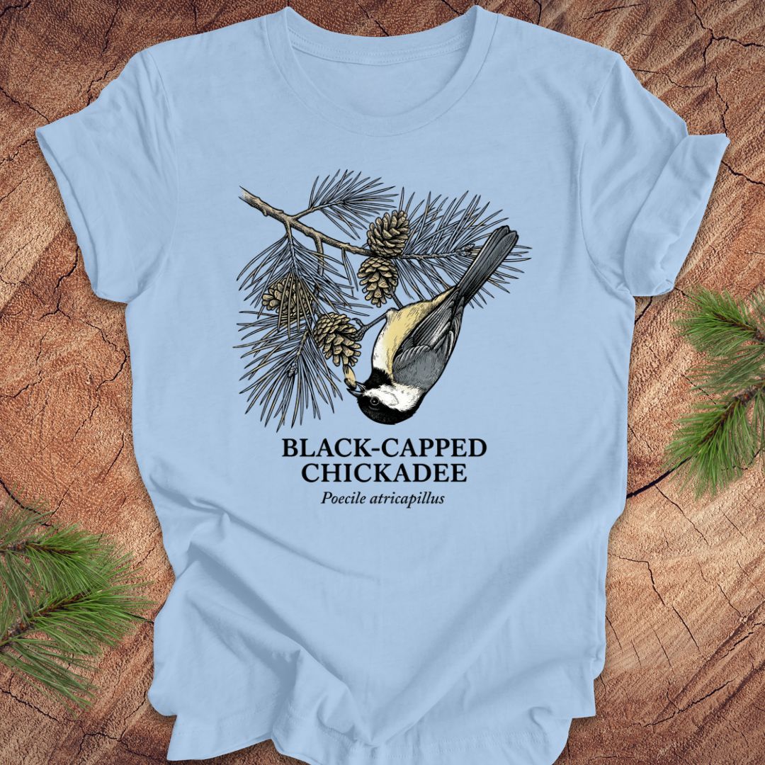 Light blue t-shirt with black-capped chickadee design on a wooden surface