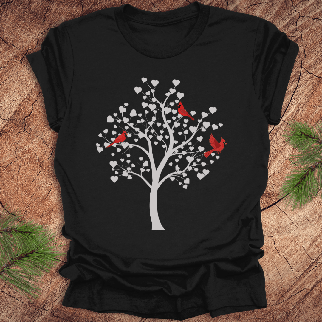 Black t-shirt with a tree design featuring cardinals and white hearts on a wooden surface.