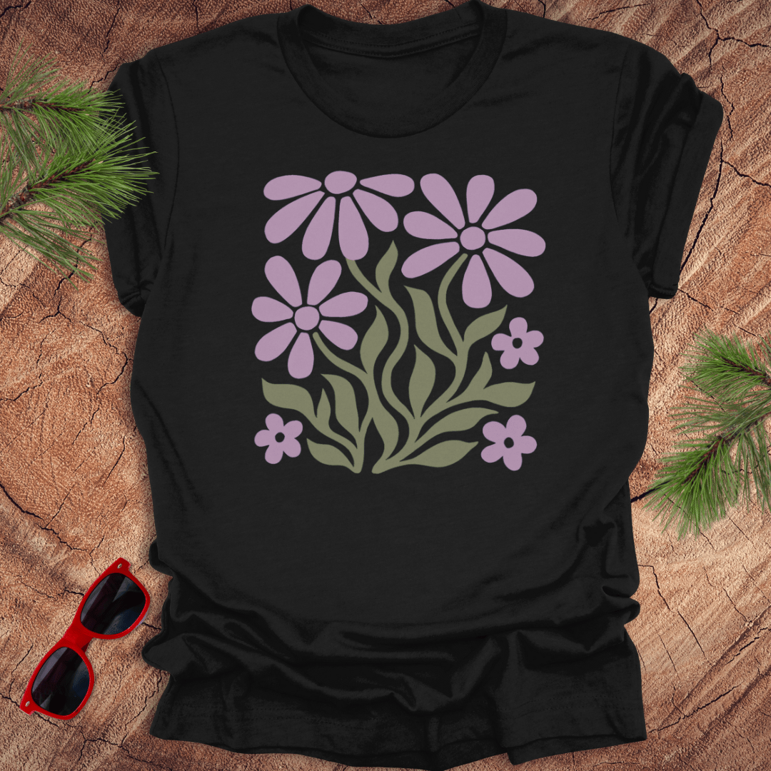 Black t-shirt with purple floral design on a wooden surface with sunglasses and greenery.