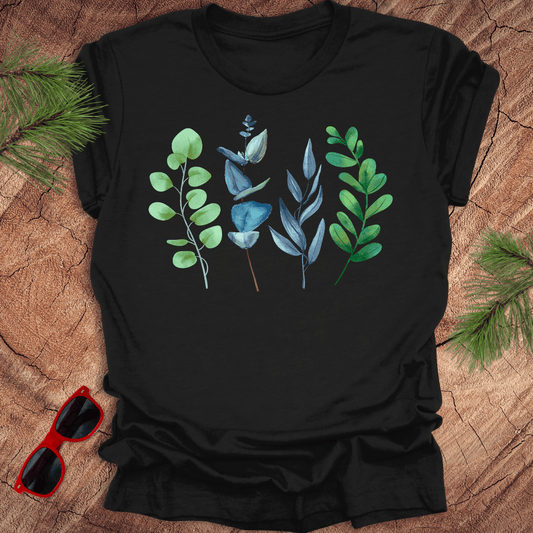 Black t-shirt with green and blue leaf designs on a wooden surface with sunglasses.