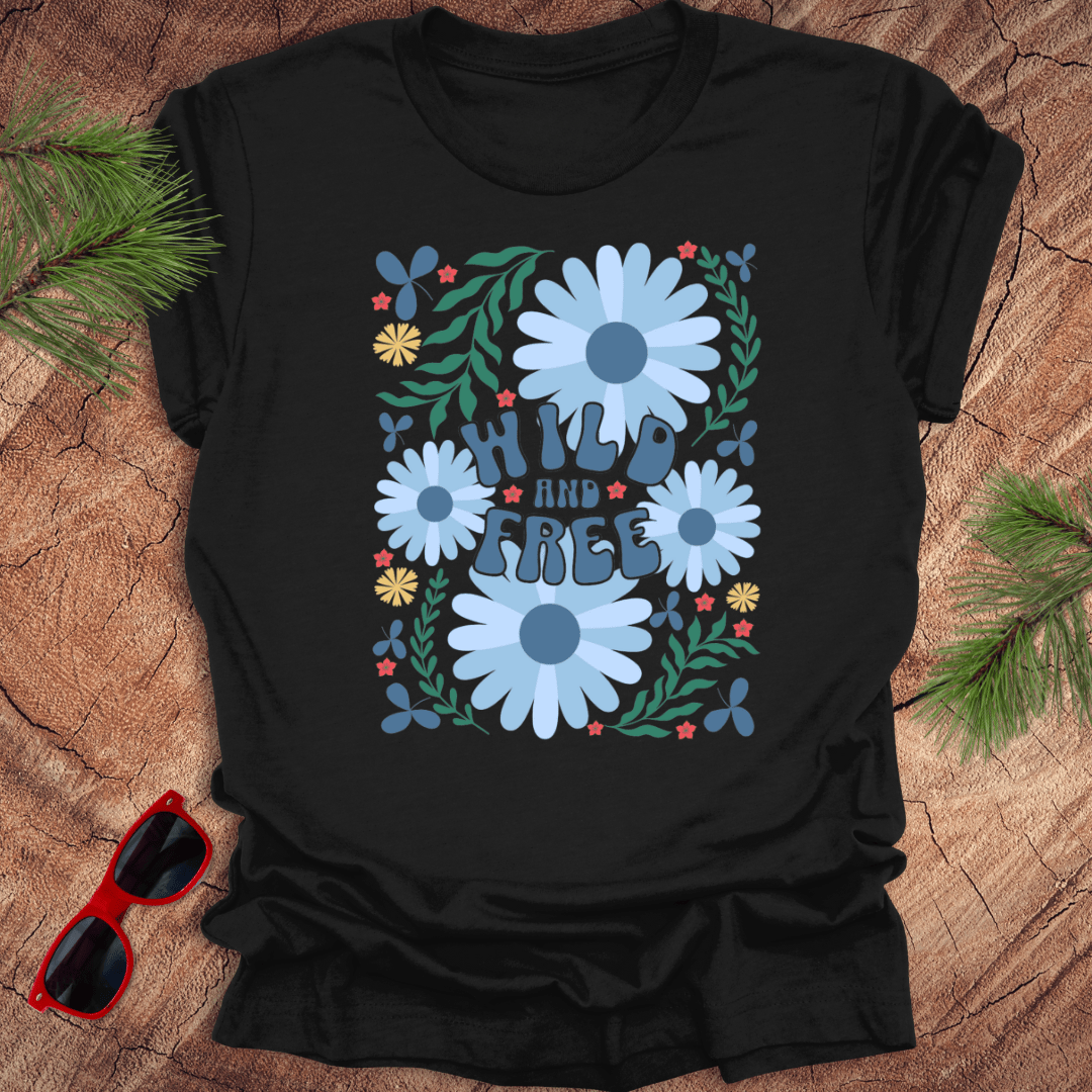Black t-shirt with floral design and 'Wild and Free' text on a wooden surface with sunglasses.