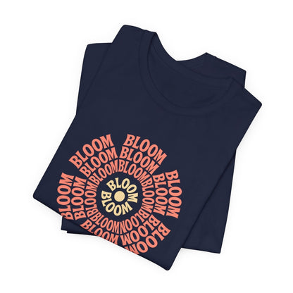 Navy blue folded t-shirt with 'BLOOM' printed in red and gold on a white background