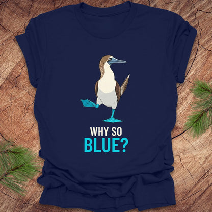 Navy blue t-shirt with a blue-footed booby bird graphic and 'Why So Blue?' text on a wooden surface.