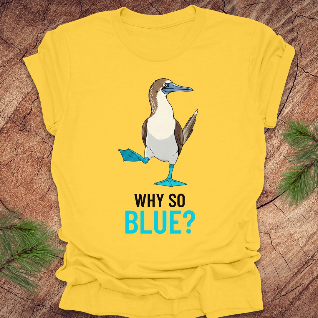 Yellow t-shirt with a blue-footed booby bird graphic and 'Why So Blue?' text on a wooden surface.
