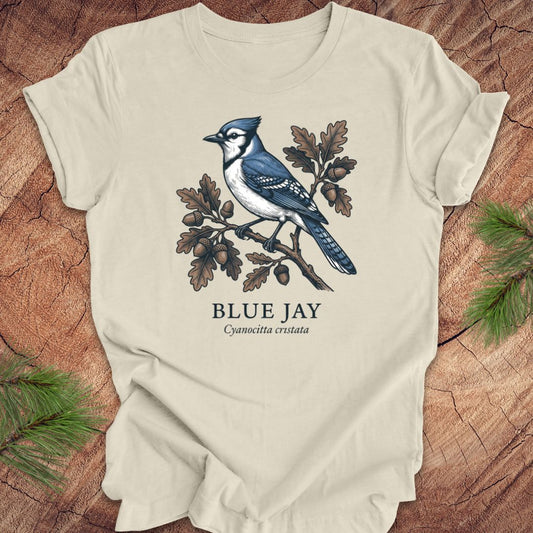 Beige t-shirt with a blue jay illustration on a wooden surface