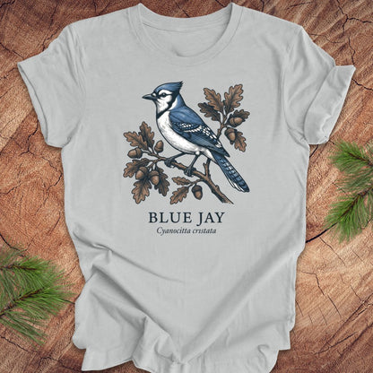Gray t-shirt with a blue jay illustration on a wooden surface