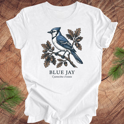 White t-shirt with a blue jay graphic and text on a wooden surface
