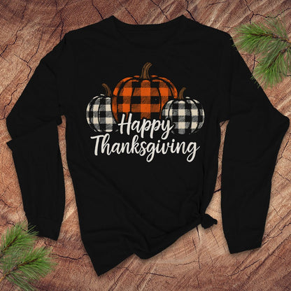 Black long-sleeve tshirt with 'Happy Thanksgiving' text and plaid pumpkins on a wooden surface.