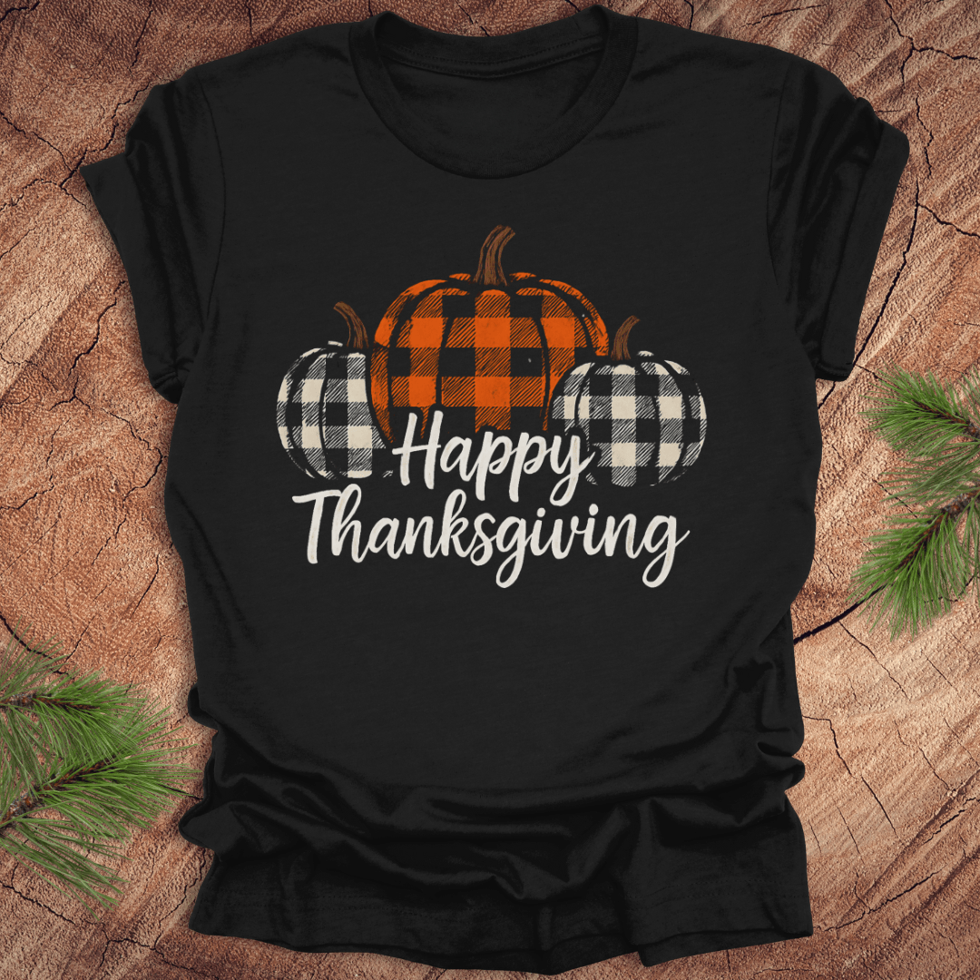 Black t-shirt with 'Happy Thanksgiving' and checkered pumpkins design on a wooden surface.