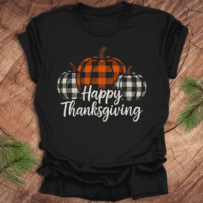 Black t-shirt with 'Happy Thanksgiving' and checkered pumpkins design on a wooden surface.