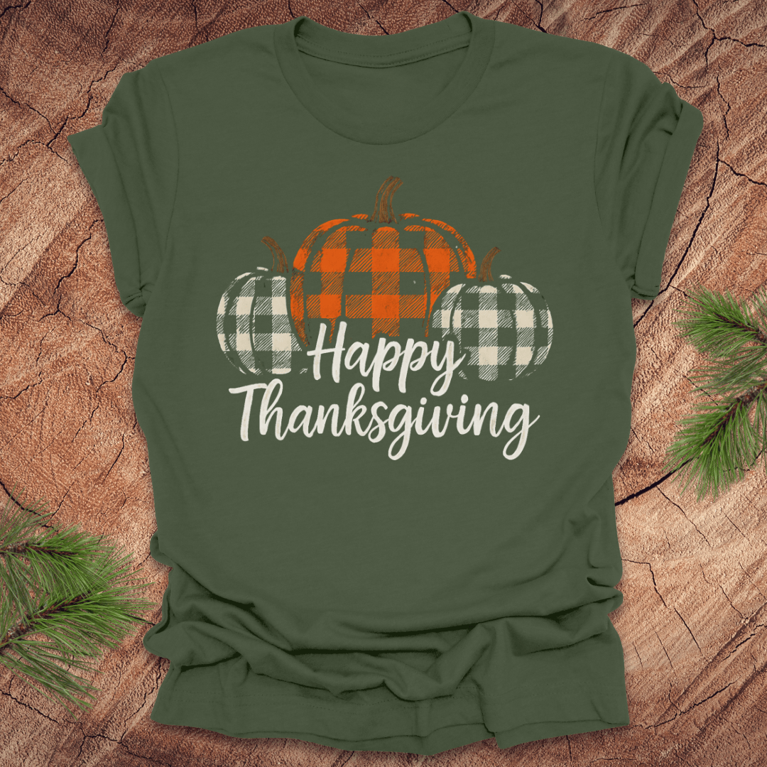 Green t-shirt with plaid pumpkins and 'Happy Thanksgiving' text on a wooden surface.