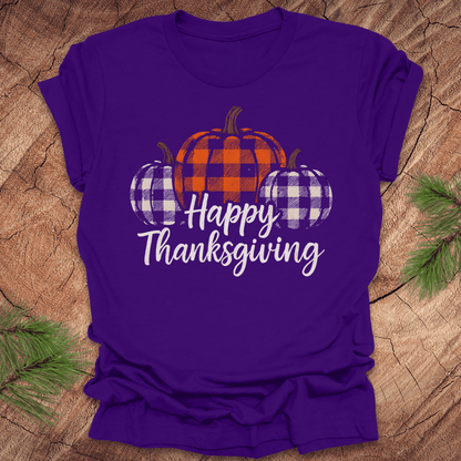 Purple t-shirt with plaid pumpkins and 'Happy Thanksgiving' text on a wooden surface.