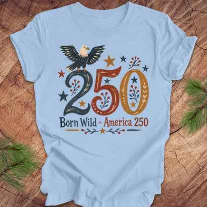 Light blue t-shirt with an eagle design and '250 Born Wild America 250' text on a wooden surface.
