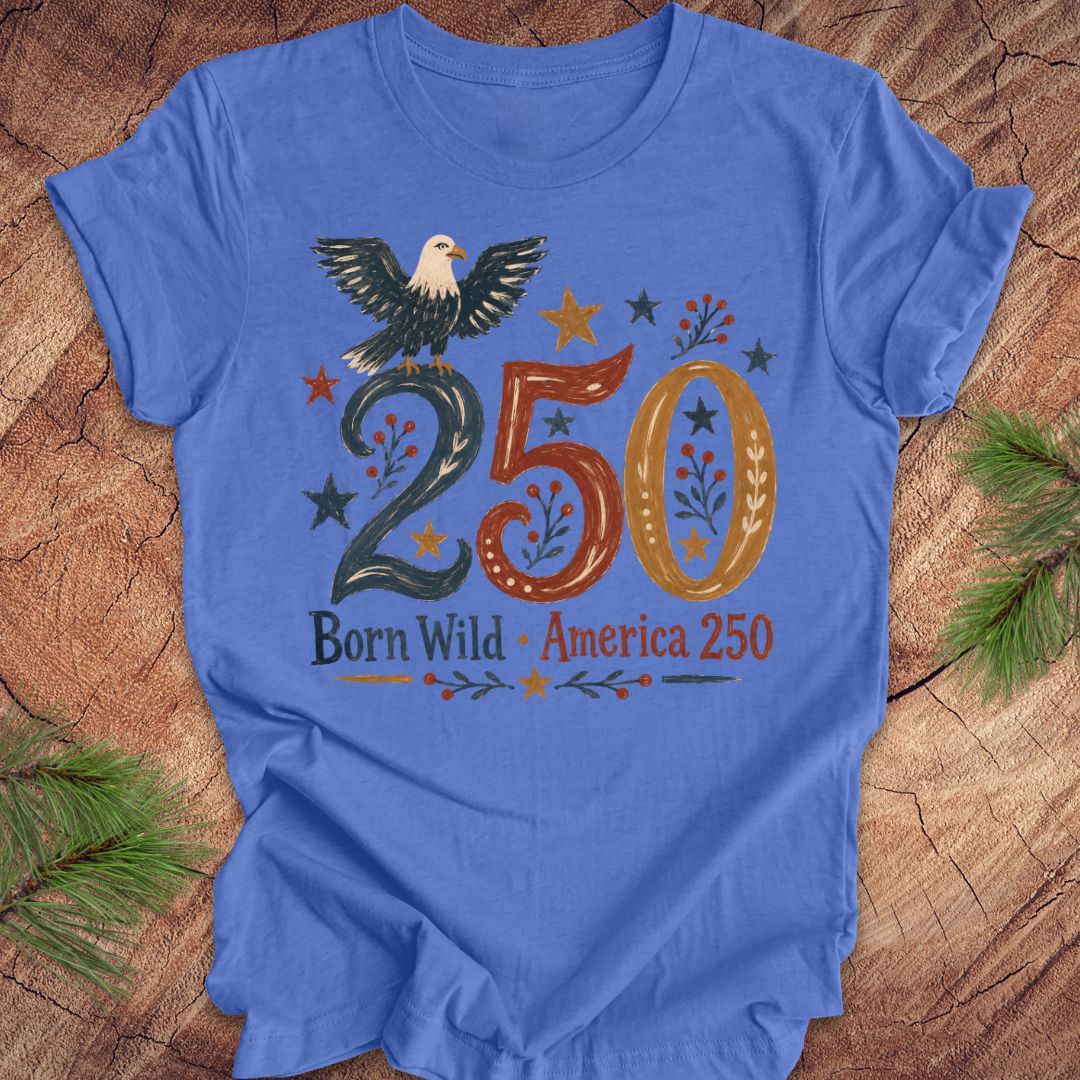 Blue t-shirt with an eagle design and '250 Born Wild America 250' text on a wooden surface.