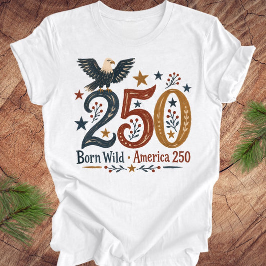 White t-shirt with an eagle and '250 Born Wild America 250' design on a wooden surface.