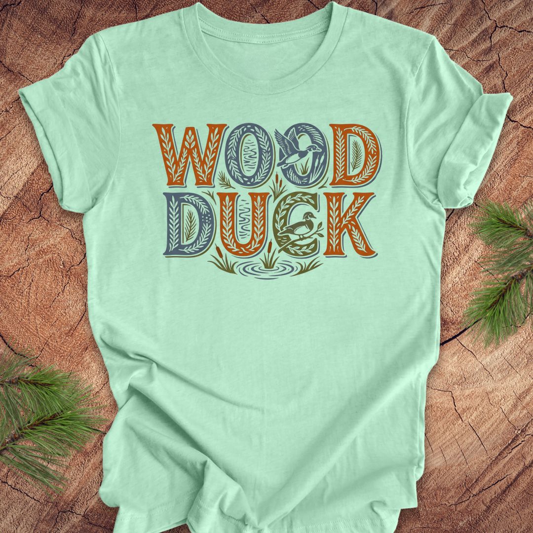 Light green t-shirt with 'Wood Duck' text on a wooden surface