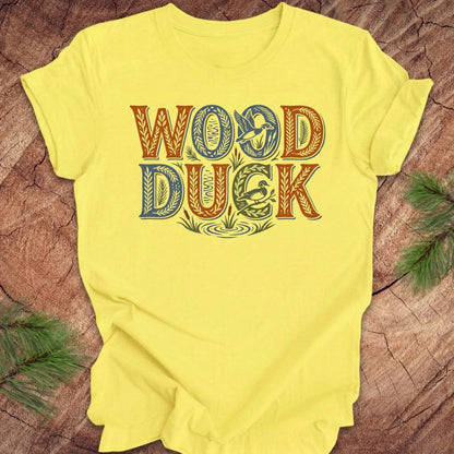 Yellow t-shirt with 'WOOD DUCK' text on a wooden surface