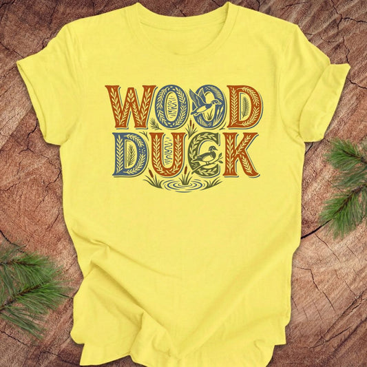 Yellow t-shirt with 'WOOD DUCK' text on a wooden surface
