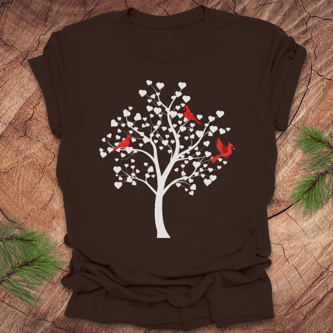Brown t-shirt with a tree design featuring cardinals and white hearts on a wooden surface.