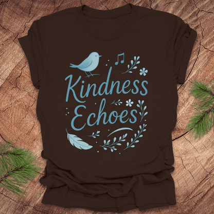 Brown t-shirt with birds and flowers and text, 'Kindness Echoes' design on a wooden surface.
