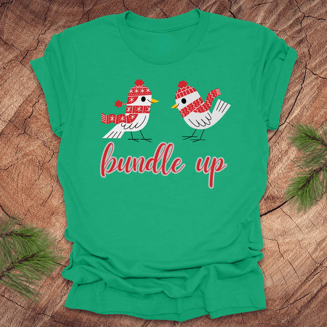 Green t-shirt with two birds with hats and scarves and text, 'Bundle up' on a wood background